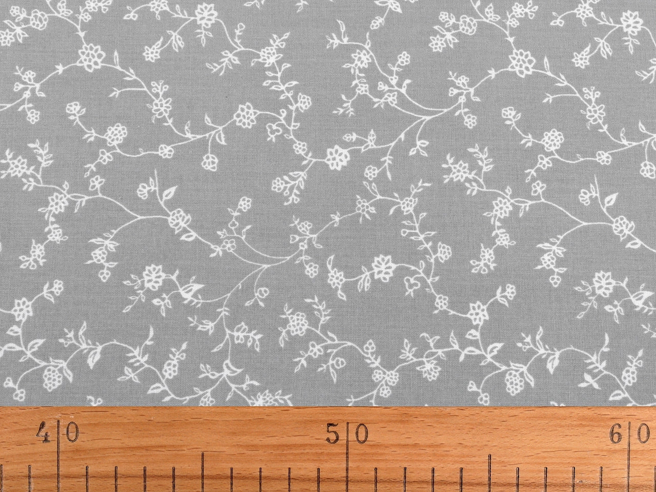 Image d’un tissu 100 % coton - tiges fleuries blanches sur fond rouge, 125 g/m² – disponible chez Šarlotes audumi