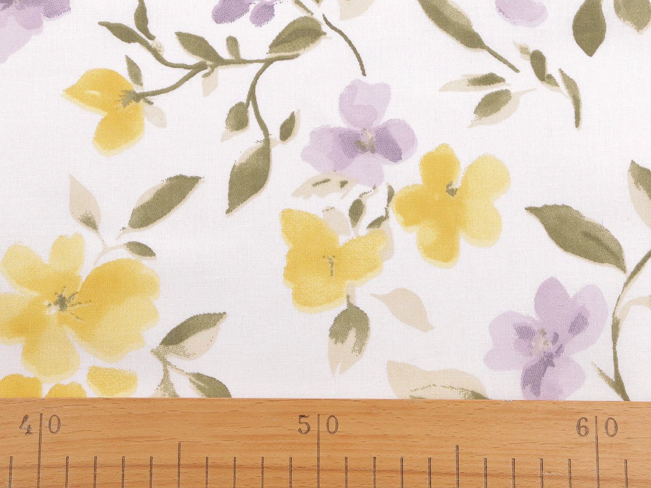 Image d’un tissu 100 % coton avec des fleurs jaunes et lilas – disponible en ligne chez Charlotte Tissus