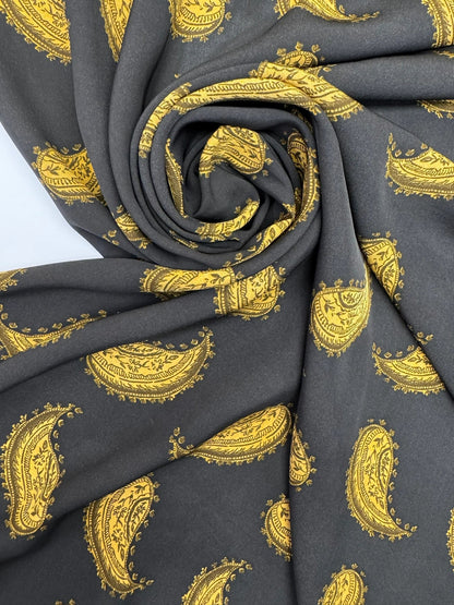 Bild eines italienischen 100% Viskose-Chiffonstoffs mit goldenem Paisley-Muster auf schwarzem Hintergrund – online erhältlich bei Šarlotes audumi