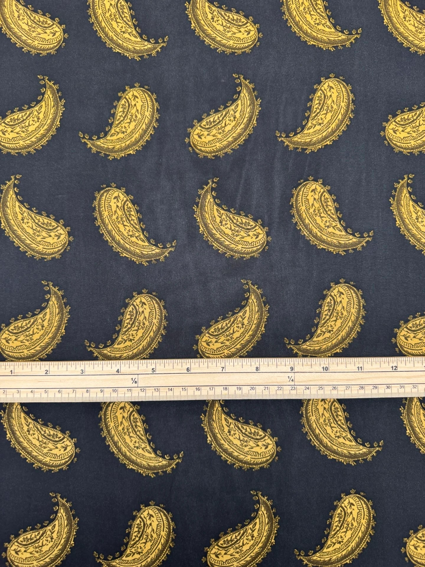 Bild eines italienischen 100 % Viskose-Chiffonstoffs mit goldenem Paisley-Muster auf schwarzem Hintergrund – online erhältlich bei Šarlotes audumi