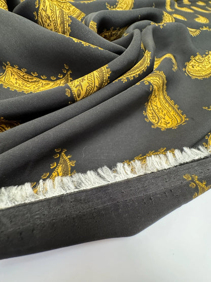 Bild mit 100 % Viskose-Chiffonstoff aus Italien mit goldenem Paisley-Muster auf schwarzem Hintergrund – online erhältlich bei Šarlotes audumi