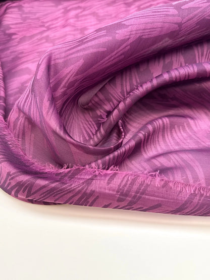Image of Italian silk satin fabric in pink and lilac tones with an abstract pattern – available online at Šarlotes audumi