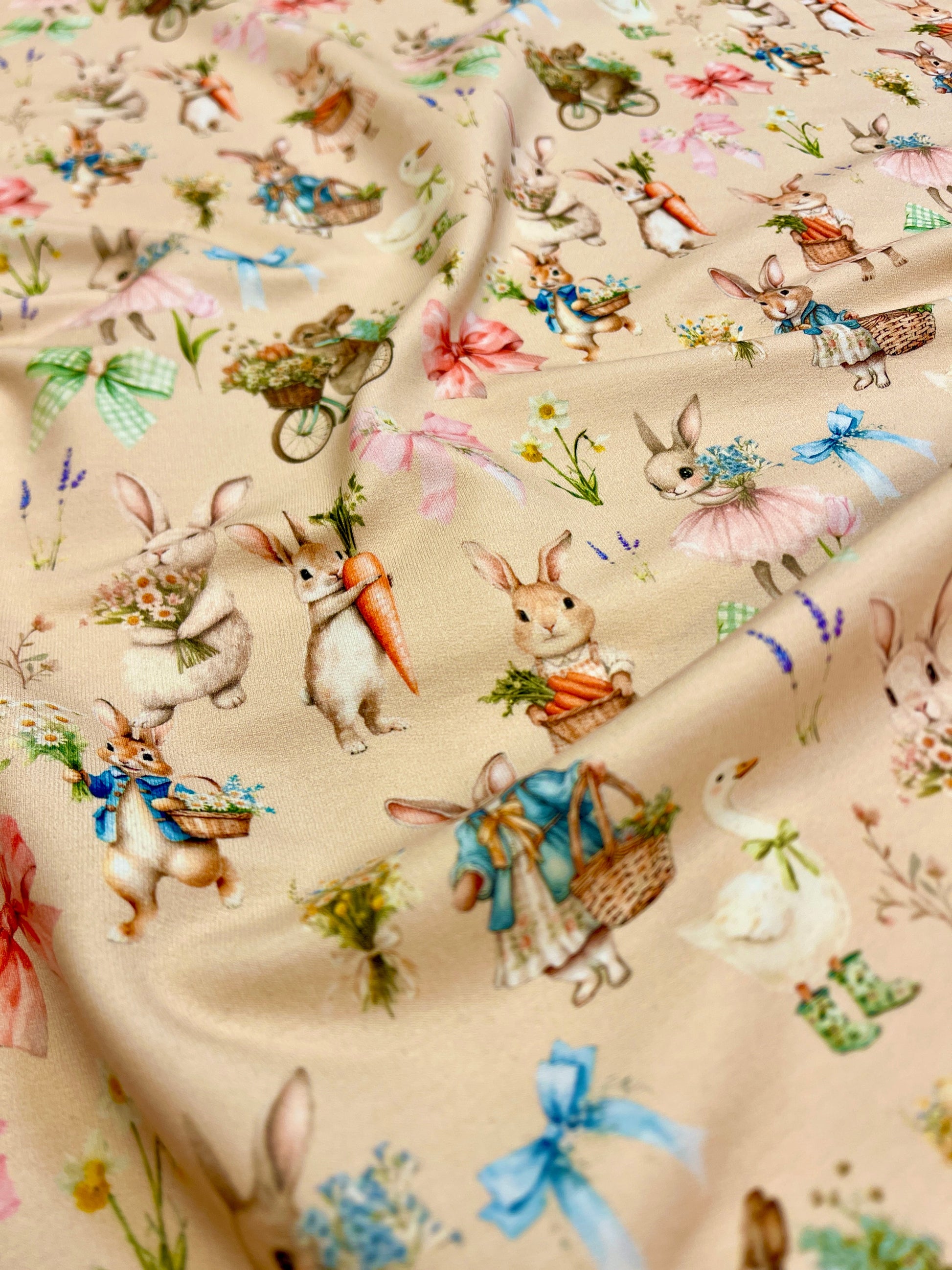 Attēls ar Kokvilnas cilpiņtrikotāža - trusīši uz bēša fona 250 g/m² – pieejams Šarlotes audumi