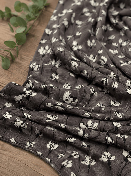 Attēls mit Baumwolljersey-Blumenmuster auf graubraunem Hintergrund 210 g/m² – online erhältlich bei Šarlotes audumi