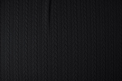 Image d’un tissu tricoté à motif de maille - tresses noires 340 g/m² – disponible chez Šarlotes audumi